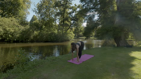 young woman doing balancing yoga exercises in beautiful park