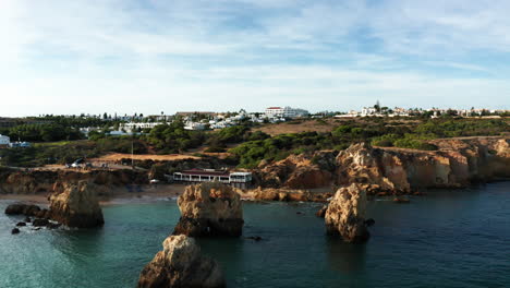 Antena:-Hermosa-Costa-Con-Playa-De-Arena,-Rocas-Sobresalientes-En-El-Océano-Y-Hoteles-De-Lujo-En-La-Cima-De-La-Colina