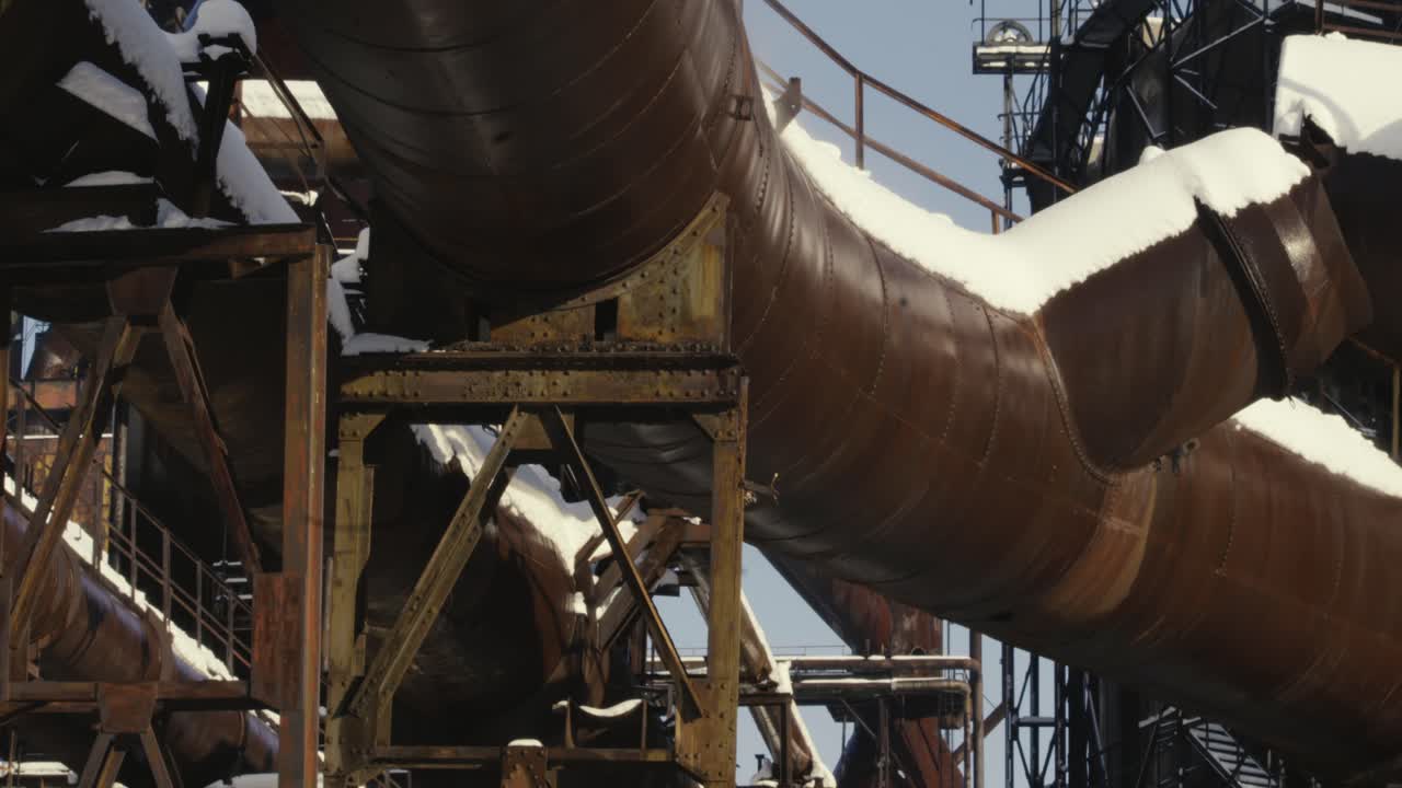 nieve y vapor derritiéndose y evaporándose de viejas tuberías oxidadas en una fábrica abandonada