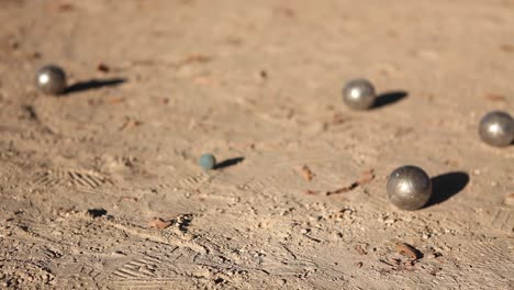 choques de bolas de metal durante un juego de petanca al aire libre. petanca jugador sosteniendo pelotas de metal en la mano y disparando en un suelo de tierra en un parque soleado en parís en la tarde de verano. impacto de metal.