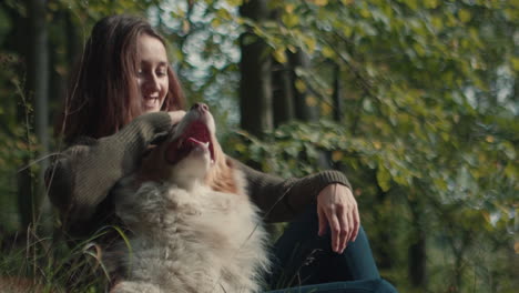 woman sitting in a meadow playing with her dog