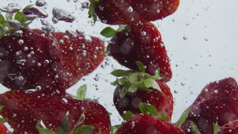 juicy strawberry floating water at white background closeup. red berries raising