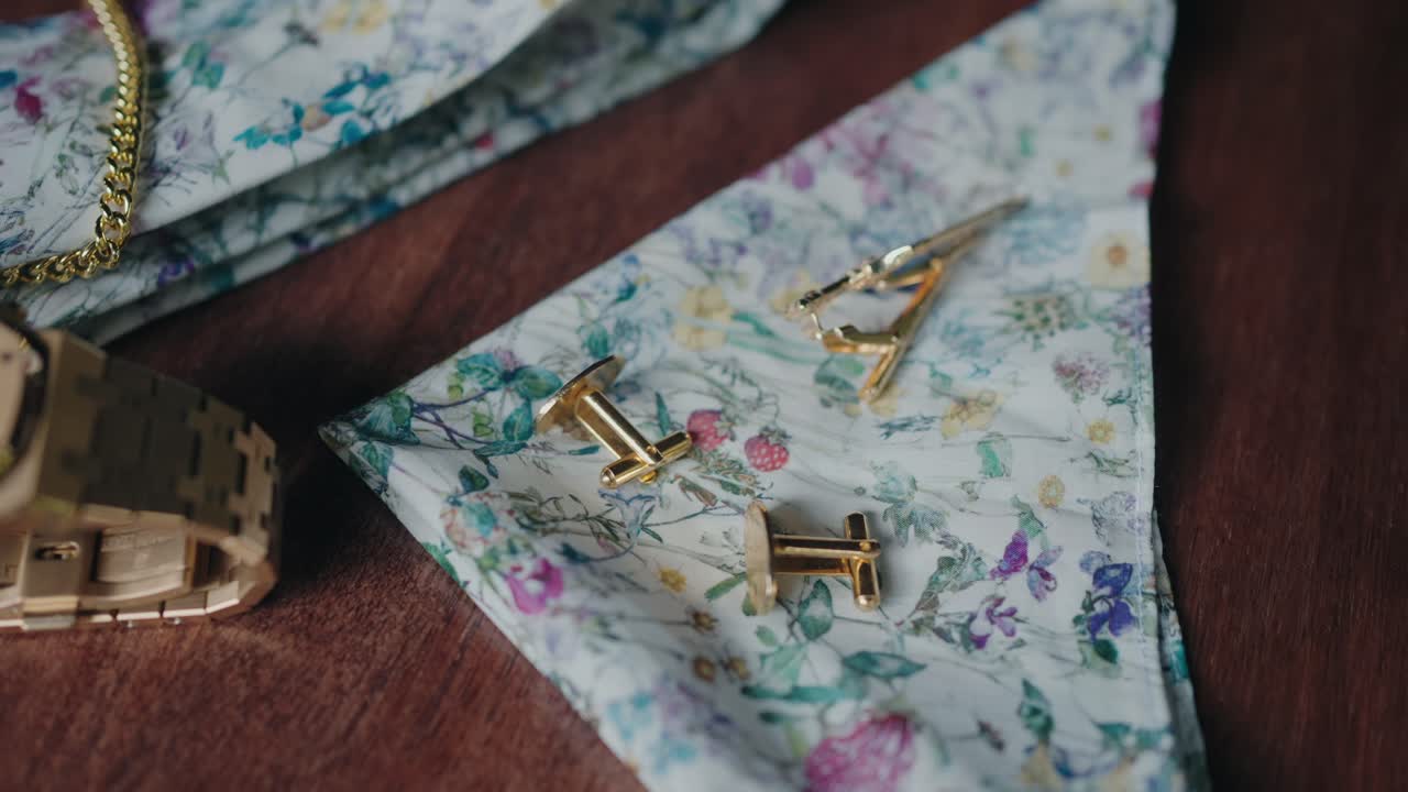 Gold cufflinks placed on floral patterned fabric