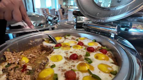 serving a hearty breakfast buffet dish with eggs, meat, and vegetables
