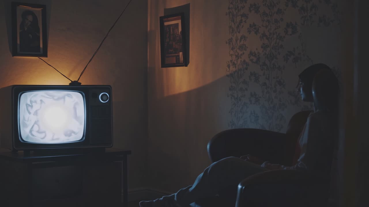 mujer viendo televisión vintage en una habitación oscura