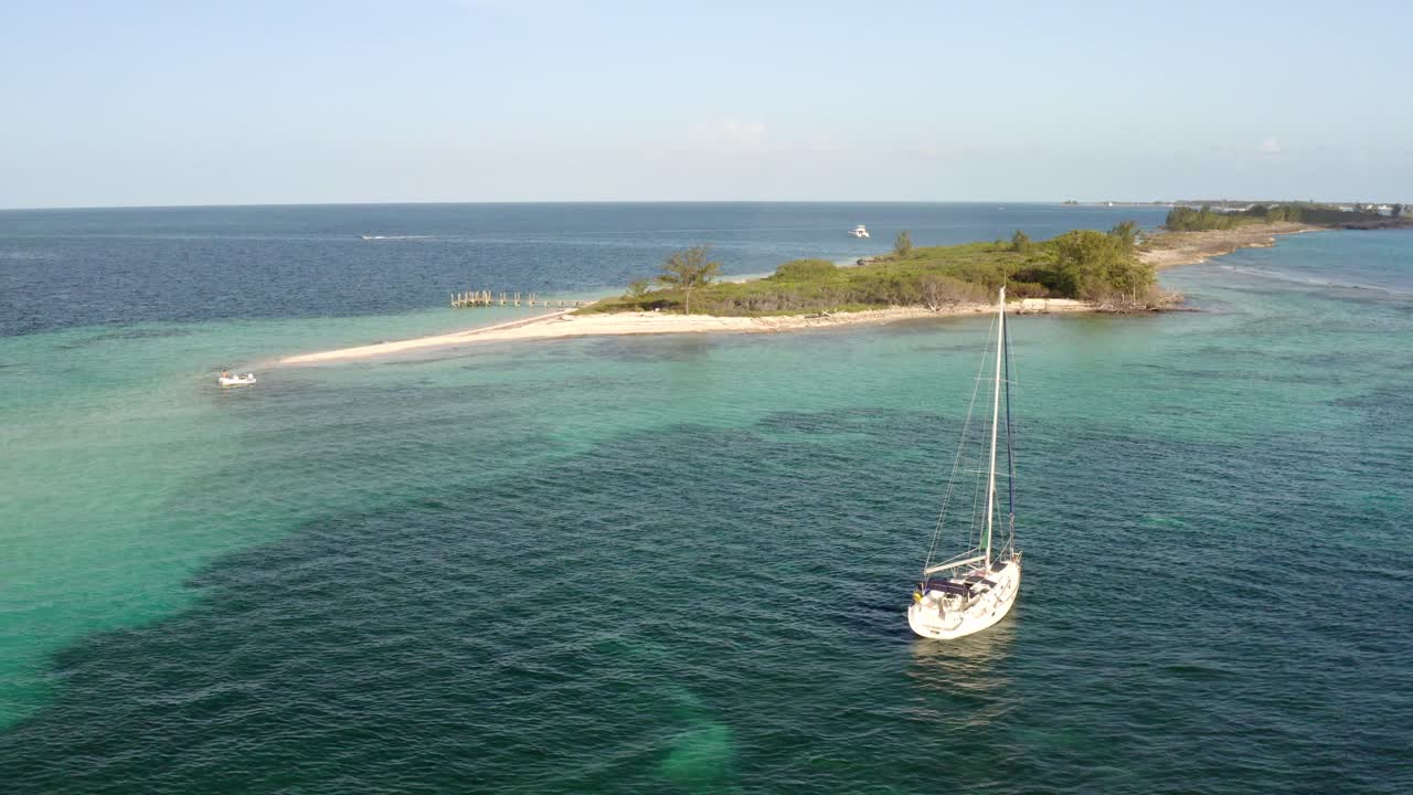 velero flotando en aguas poco profundas con un hermoso arrecife de coral en el fondo y una isla de paraíso tropical en el fondo