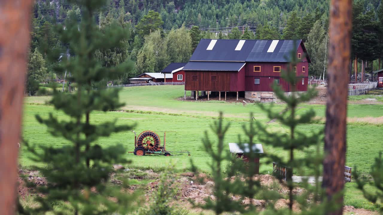 A secluded farm at the mountain foothills. A flock of sheep grazing on the lush meadow. Parallax video, bokeh background.