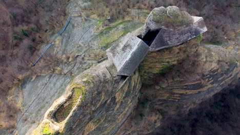 aerial view of a unique rock formation with a concrete castle structure embedded, aerial view