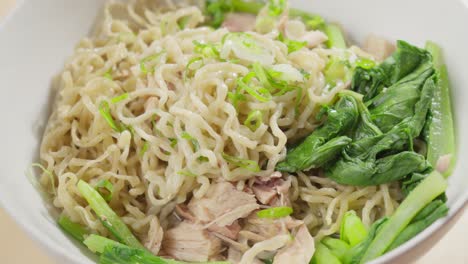 green onions sprinkled on bakmi wheat-based noodles in a bowl