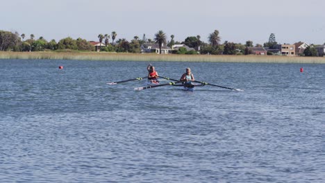 Four-senior-caucasian-men-and-women-in-rowing-boat-raising-hands-and-cheering