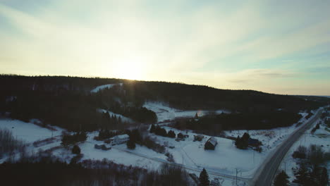 Fliegende-Drohne-über-Einer-Straße-An-Einem-Wald-Und-Einem-Zugefrorenen-See-Im-Winter-In-Kanada