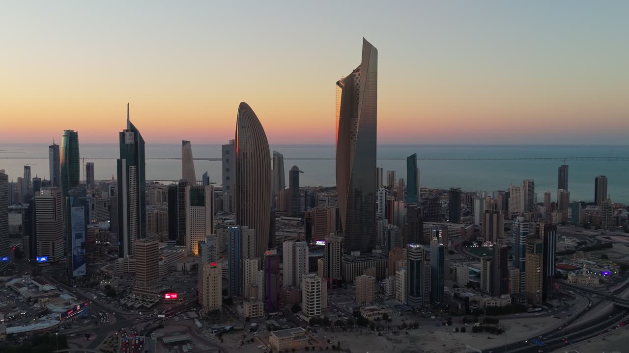 4K drone aerial of Kuwait City during golden hour. Towers silhouetted against a vibrant sunset sky over the Gulf. Ideal for real estate, tourism, and urban themes.