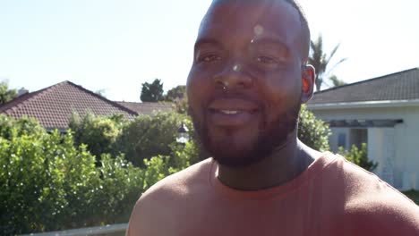 Portrait-of-happy-african-american-man-looking-at-camera-and-smiling-in-sunny-garden,-in-slow-motion