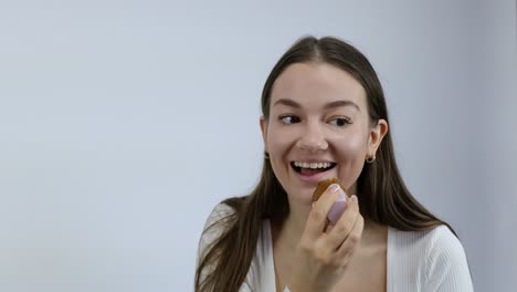 feliz y sonriente joven mujer caucásica aplicando su maquillaje delante del espejo
