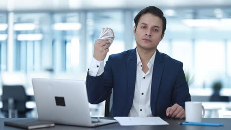 confident indian businessman using money as fan