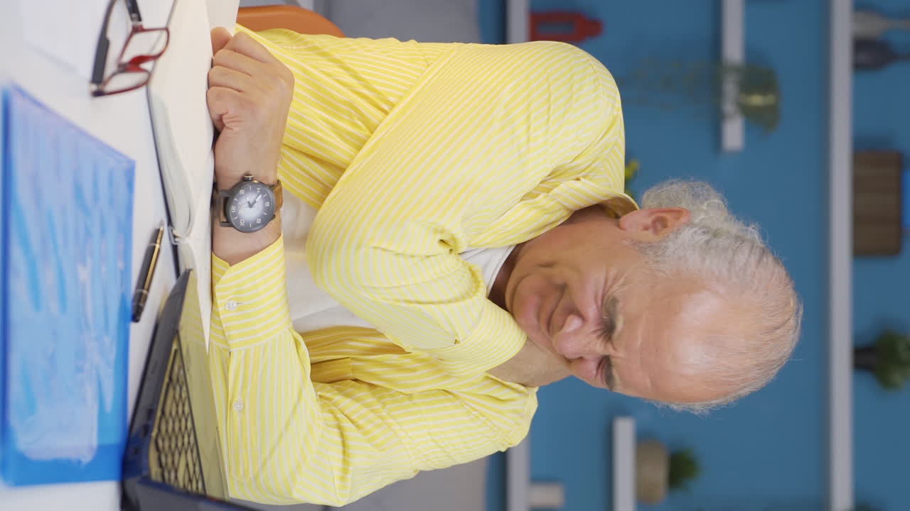 홈 오피스 근로자의 수직 비디오 노인은 어깨 통증이 있습니다.