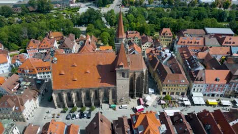 4k aerial drone video of farmers market in the courtyard of the st. johannis kirche church in downtown ansbach, germany