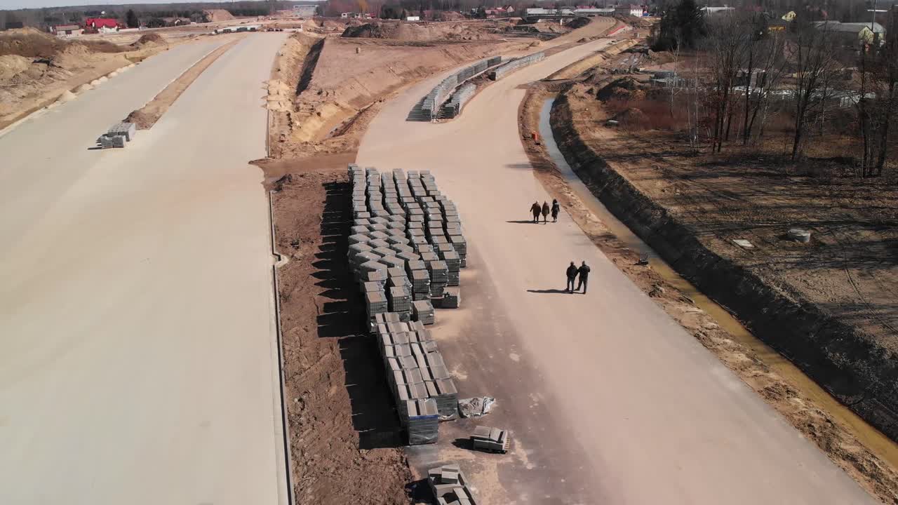 Aerial backwards shot of a group of people on the road construction site