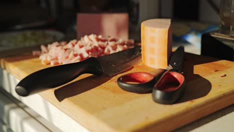 wooden cutting board with diced ham, kitchen knife and scissors in sunset glow