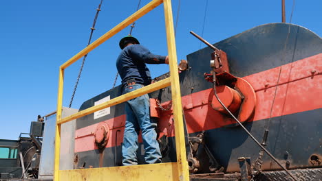 rear view of a man standing at the deck of the machine with oil rig. low angle view at the natural resources production worker.