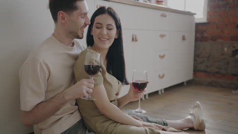 una pareja disfrutando del vino en la cocina.