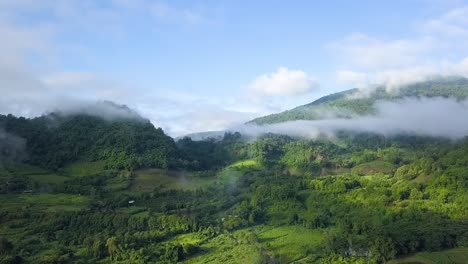 Misty-Mountains-with-Blue-Sky-and-Lush-Green-Farmland-in-Northern-Thailand-Aerial