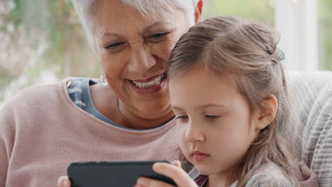 little girl showing grandmother how to use smartphone teaching granny modern technology intelligent child helping grandma with mobile phone at home 4k