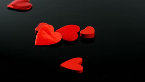 formas de corazones rojos que caen en la superficie negra 4k