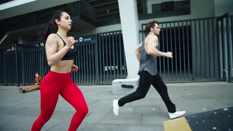 Fitness-couple-running-together-on-urban-street.-Man-training-obstacles-run.