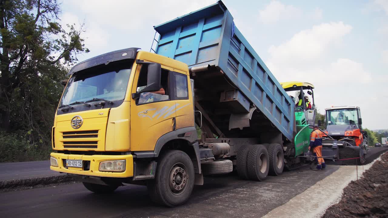 VINNYTSIA, UKRAINE - SEPTEMBER 10, 2018: unloading asphalt into the asphalt paver