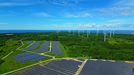 Massive-solar-panel-field-with-many-wind-turbines-in-background,-aerial-view