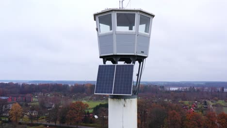 Antigua-Torre-De-Vigilancia-De-Bomberos-Con-Instalación-De-Paneles-Solares-Vista-Aérea-Del-Poste-Descendente-Al-Paisaje-Rural-Otoñal