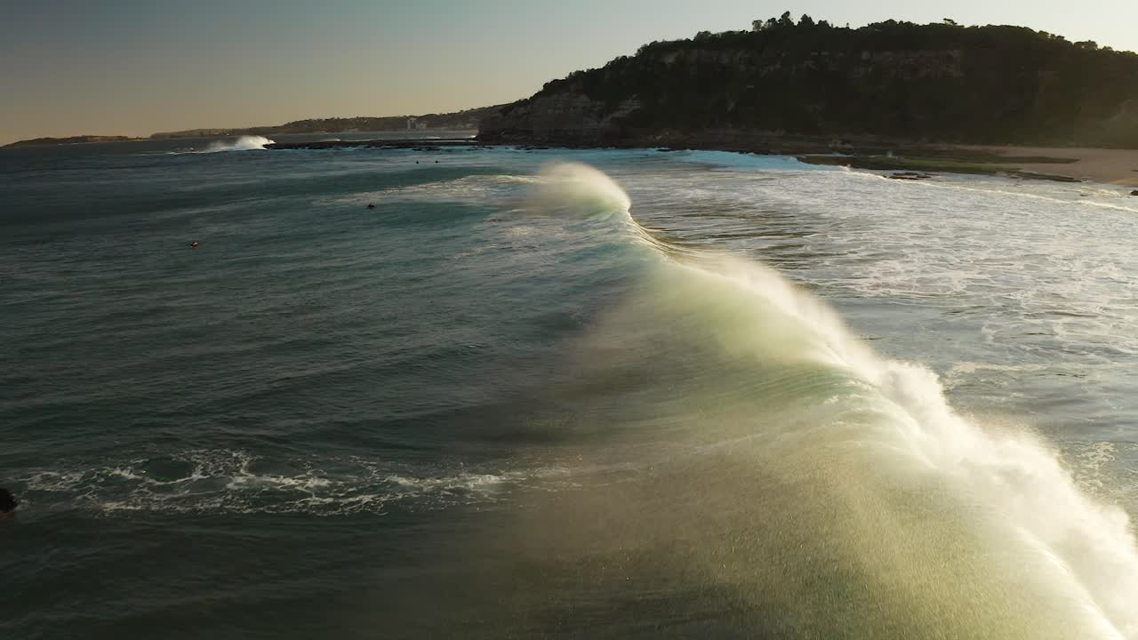 aerial de la playa al atardecer, la ola del océano rompiendo por detrás en cámara lenta en sídney, australia