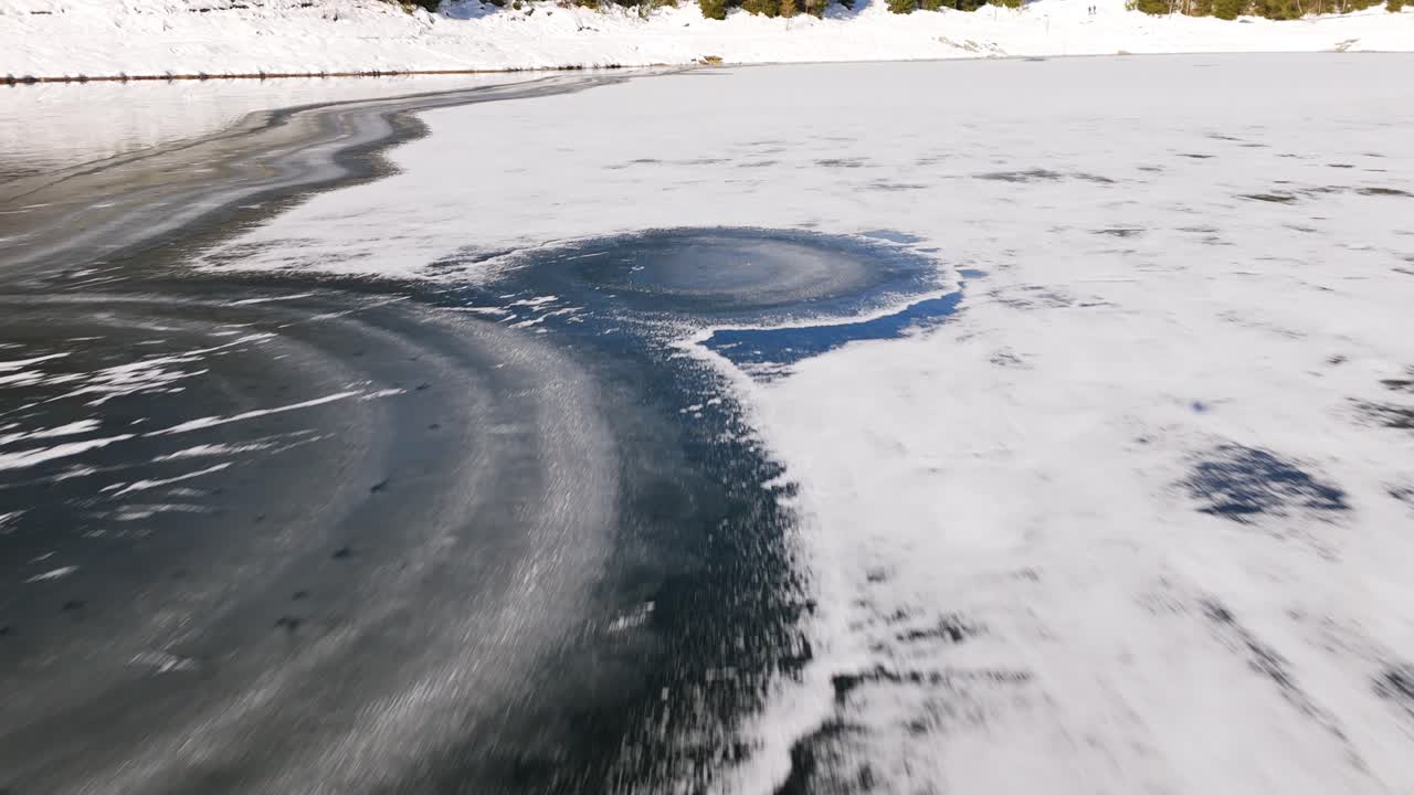 Drone flying along frozen banks of Pal&ugrave; lake in Valmalenco, Italy