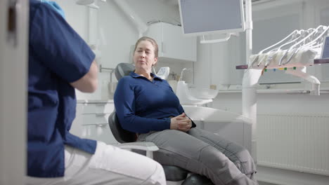 female patient listens to prognosis from dentist after oral exam, slider