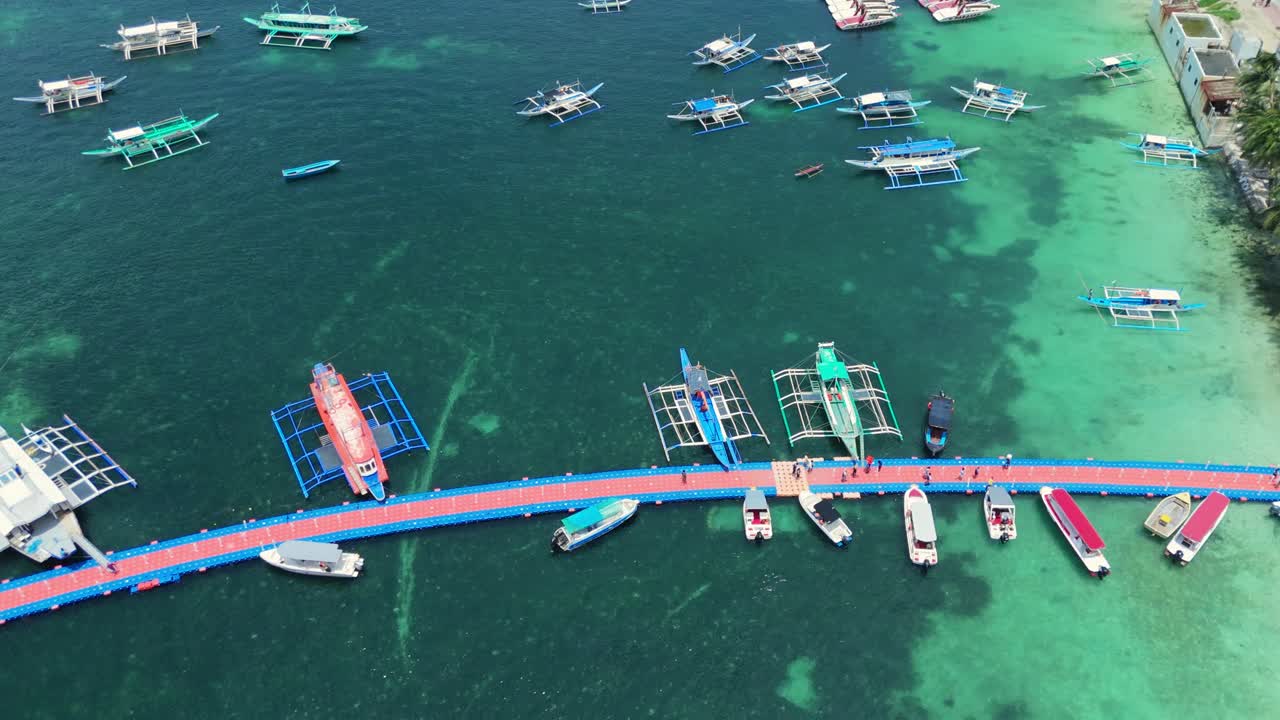 Aerial of Boracay floating pier with boats, palm-lined coastline, and turquoise waters. Ideal for travel, maritime, and tropical destination visuals