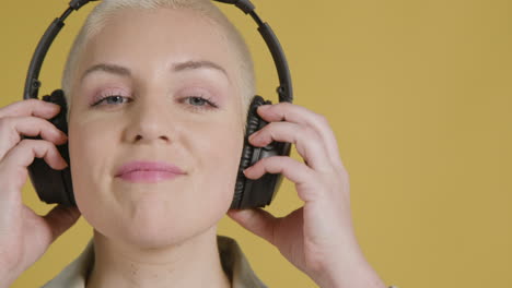 modelo femenino posa con un par de auriculares para colocar sobre las orejas