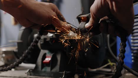 Close-up-shot-of-mechanic-breaking-a-chain-open-with-a-whetstone