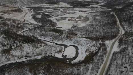 Aerial-descent-and-tilt-up-over-a-snow-covered-forest-in-a-desolate-valley