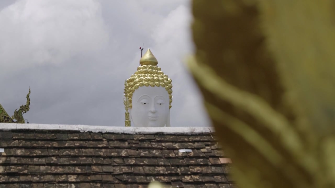 寺院の屋根から顔を出す仏像の頭部をスローモーションでスライダーが映し出す。