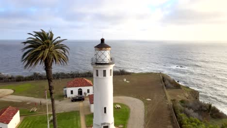 Pullback-reveal-aerial,-Point-Vicente-Lighthouse-away-from-ocean,-palm-trees,-Rancho-Palos-Verdes