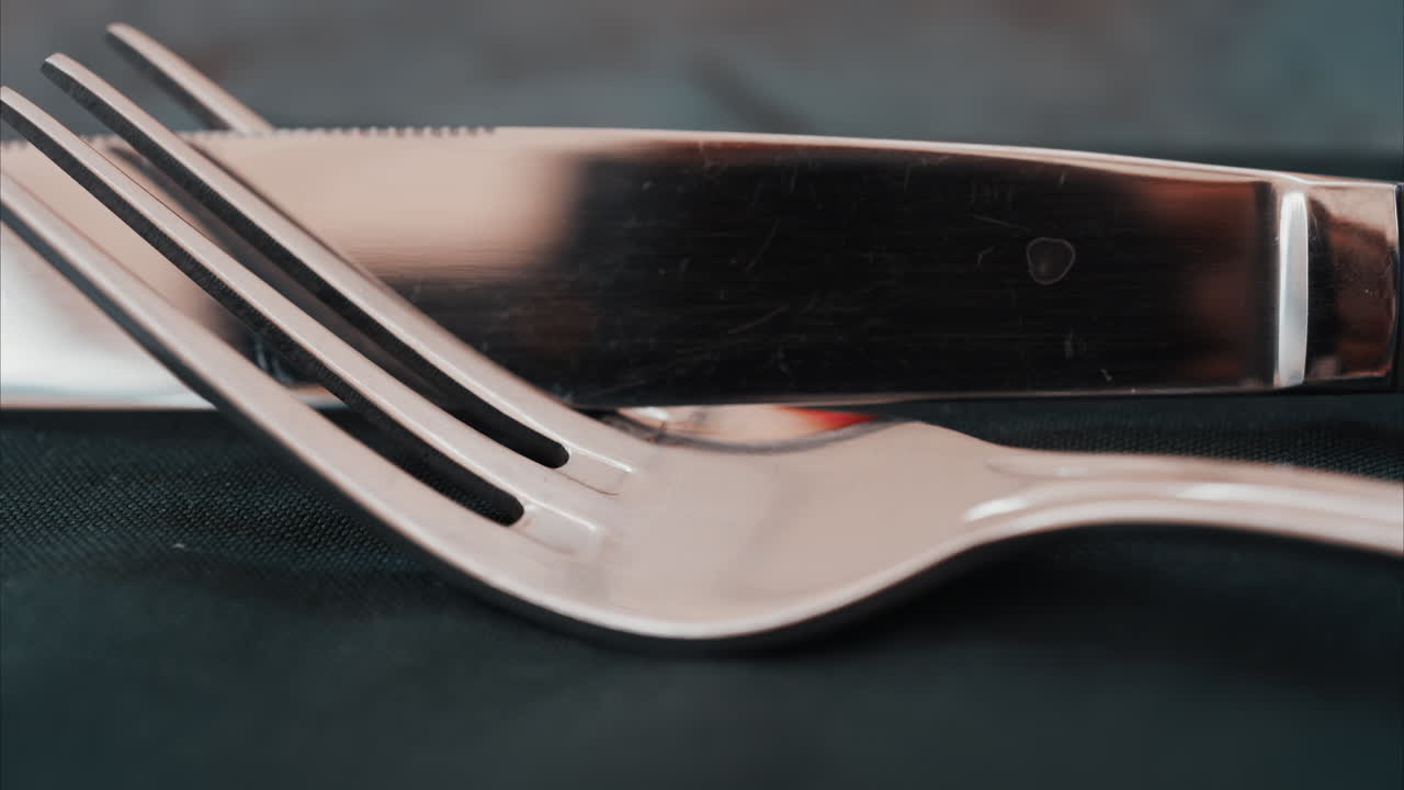 Close up of silver cutlery placed neatly on a dark napkin at a restaurant