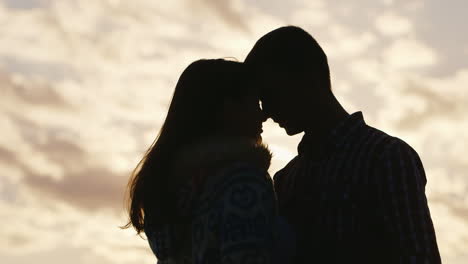 Silueta-De-Una-Joven-Pareja-De-Enamorados-En-El-Fondo-Del-Cielo-Y-El-Abrazo-Del-Sol-Tocan-Sus-Frentes