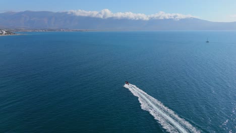 speedboat cuts through the open ocean on a sunny day with distant mountains on the horizon