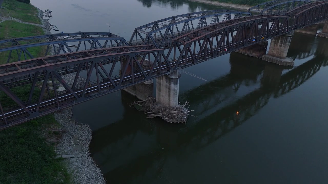 Po River beneath Ponte di Ferro railway and road bridges marking the Lombardy–Emilia-Romagna border. Record low water exposes vast sandbanks during the June 2026 heatwave. Slow aerial drone pan.