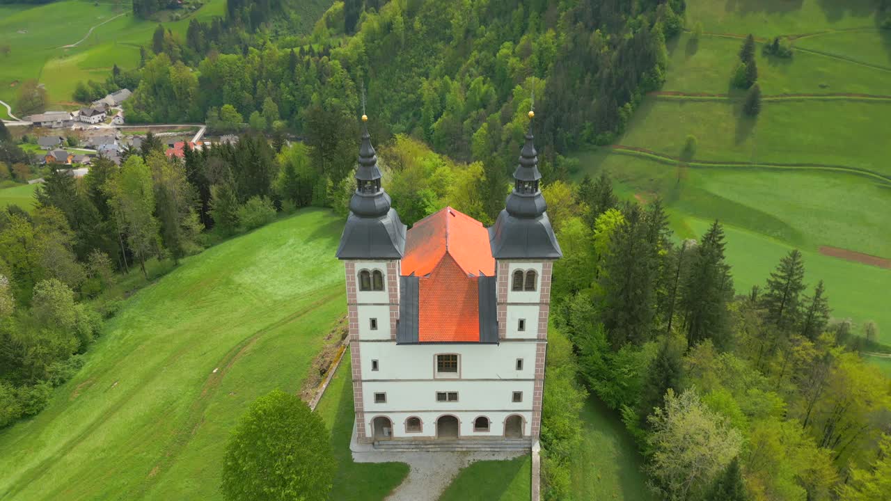 Ripresa aerea con movimento tilt up della chiesa di Cerkev Volbenka in Slovenia durante una giornata di sole
