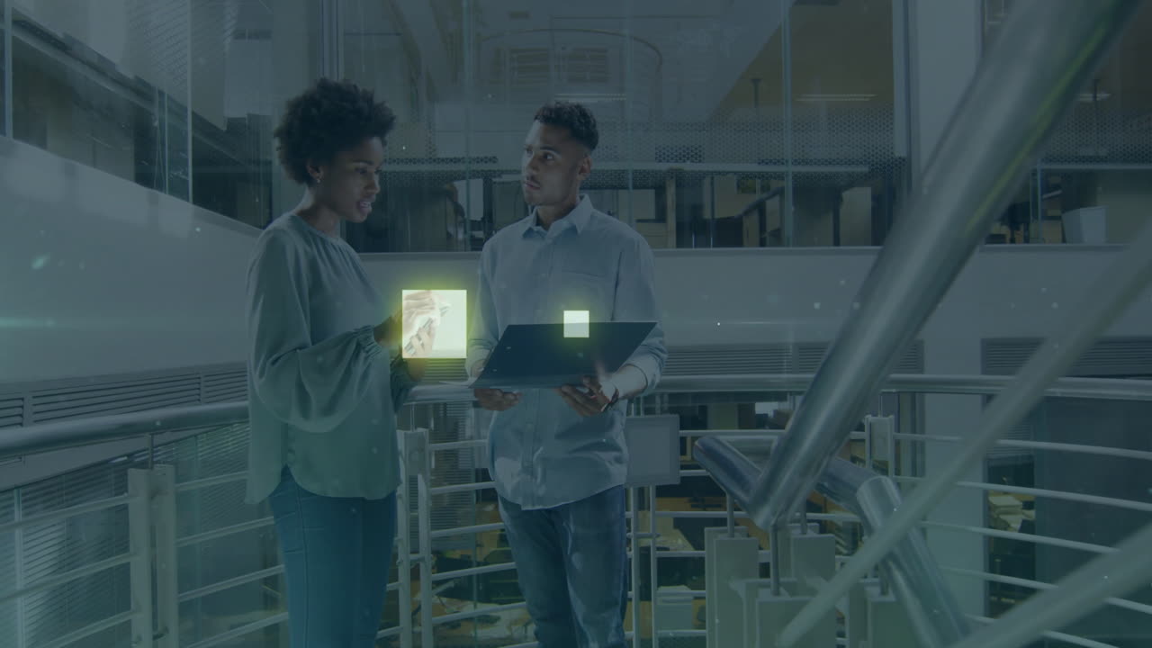 Discussing animation, two people using tablet and laptop in modern office