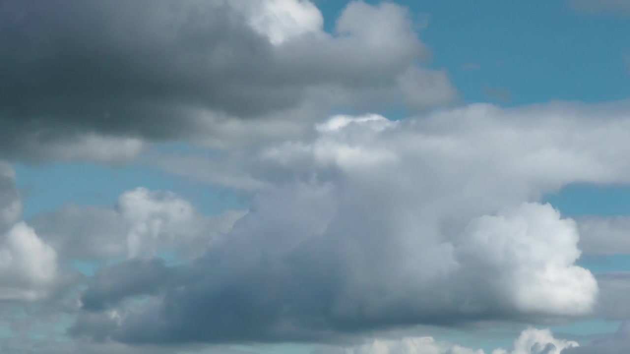 Timelapse of fluffy white cumulus clouds moving fast across a bright blue summer sky over the netherlands. bright and peaceful fair weather cloudscape.