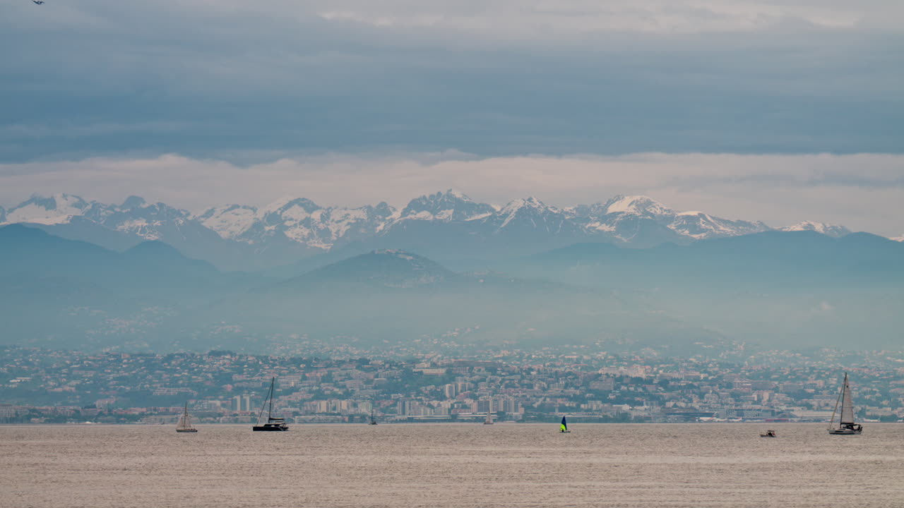 Antibes, France - May 6, 2025: Distant view of multiple boats moving on the sea with the city and the mountains on the background