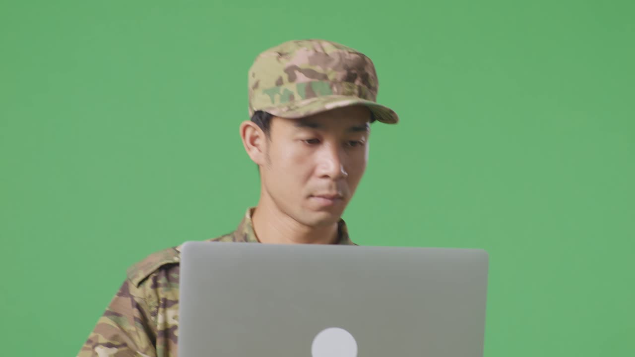 녹색 화면 배경 스튜디오에서 는 동안 노트북을 사용하는 아시아 남자 군인의 클로즈업